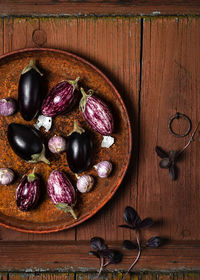 Small eggplant or aubergine vegetable with garlic and purple basil leaves on old wooden background. 