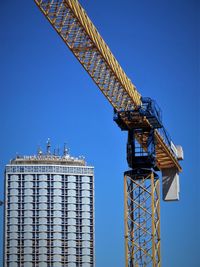 Low angle view of crane against clear blue sky