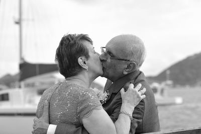 Close-up of senior couple kissing while standing against sky