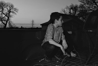 Cute boy looking away sitting on built structure