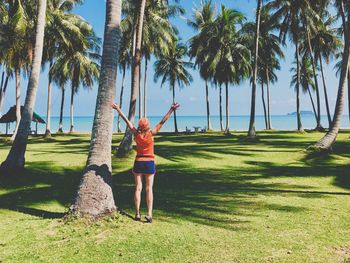 Full length of a young woman standing among palm trees