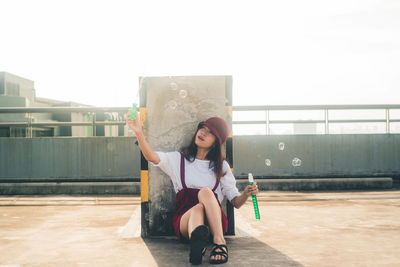 Full length of teenage girl sitting outdoors