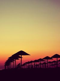 Scenic view of silhouette umbrellas against clear sky at dawn