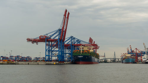 Cranes at commercial dock against sky