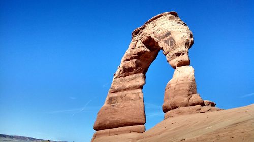 Low angle view of delicate arch against blue sky at arches national park