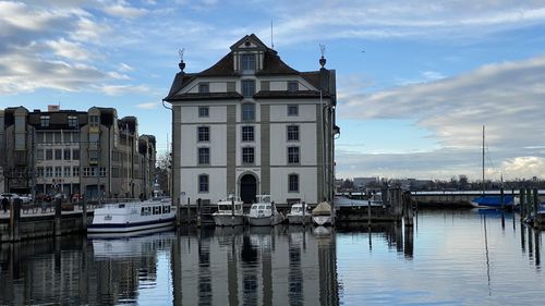 Boats moored at harbor against buildings in city