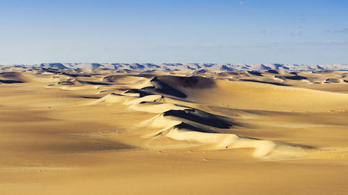 Sand dunes in desert against clear sky