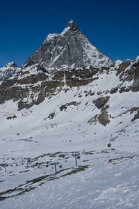 Scenic view of snowcapped mountains against clear blue sky