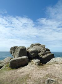 Rocks on shore by sea against sky