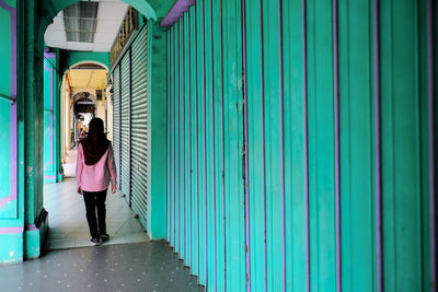 Full length rear view of woman walking in corridor of building