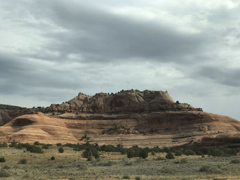 Rock formations in desert against cloudy sky