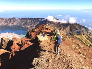 Rear view of people on rock in mountains against sky