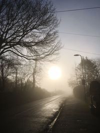 Road amidst silhouette trees against sky during sunset