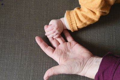 Cropped hands of parent and baby at home