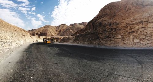 Dirt road amidst mountains against sky