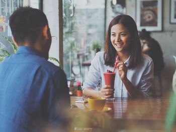 Close-up of smiling young woman sitting in restaurant