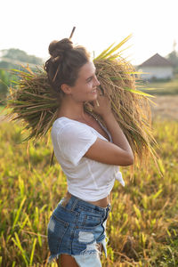 Side view of young woman sitting on field