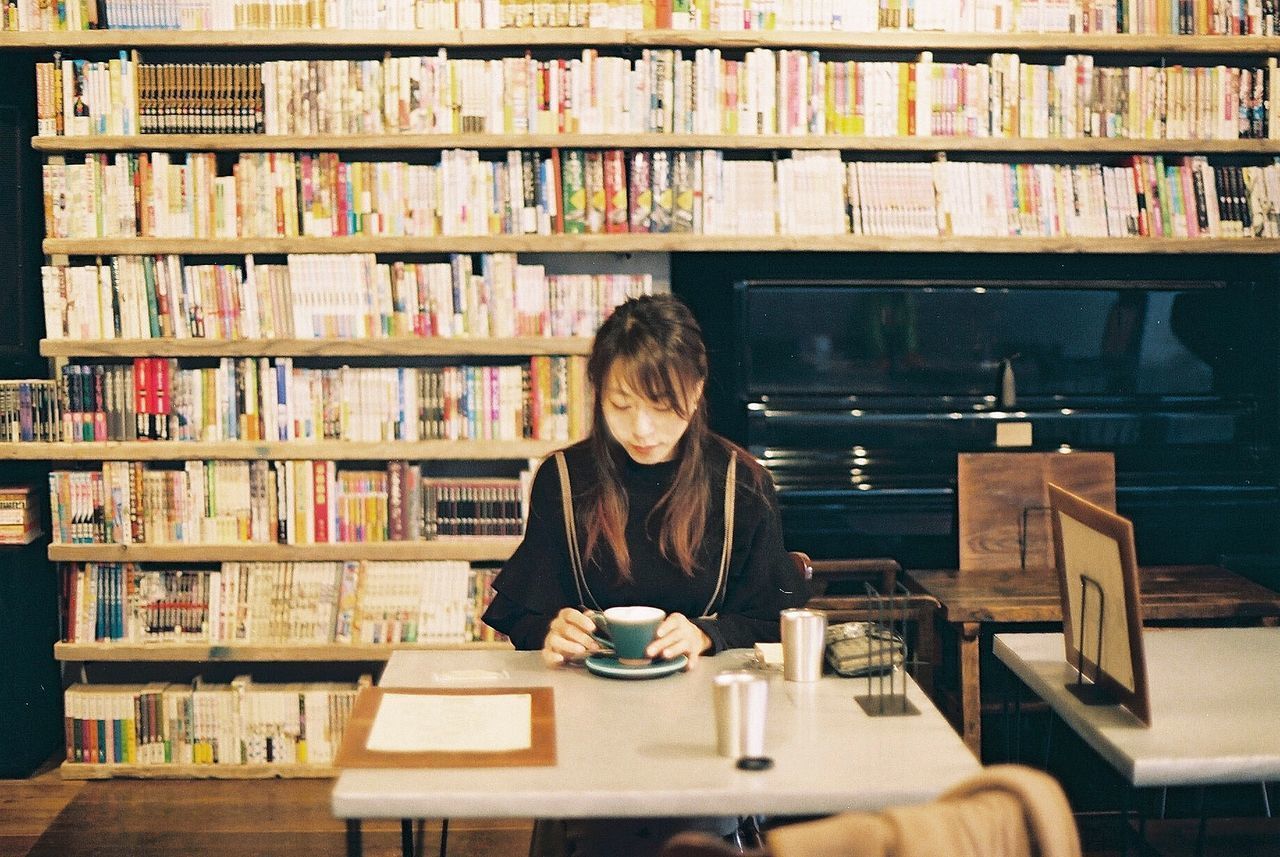 FULL LENGTH OF WOMAN SITTING ON BOOK