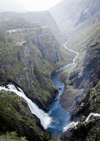 A deep ravine with a waterfall and a river