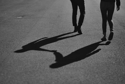 Low section of couple walking on road