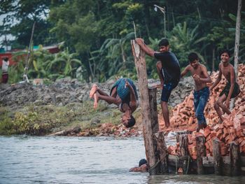 People enjoying in lake against trees