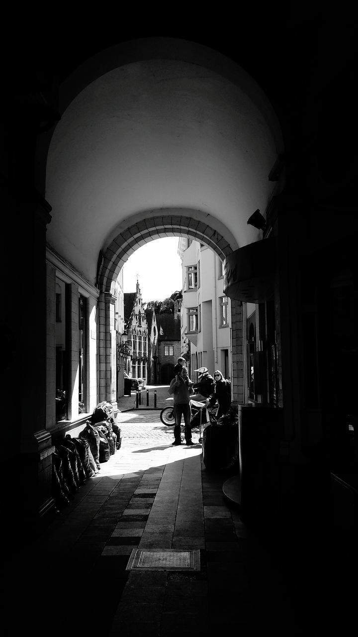 architecture, built structure, arch, building exterior, indoors, city, archway, the way forward, incidental people, walking, building, entrance, street, men, person, day, sunlight, city life, walkway