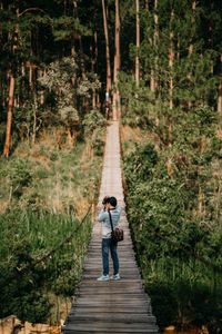 Rear view of man walking on footpath in forest