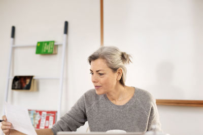 Concentrated woman holding paper while working at home