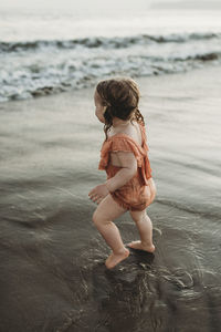 Young toddler girl with pigtails walking into the ocean