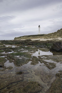 Lighthouse by sea against sky