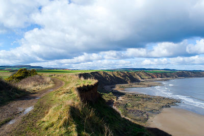 Scenic view of landscape by sea against sky