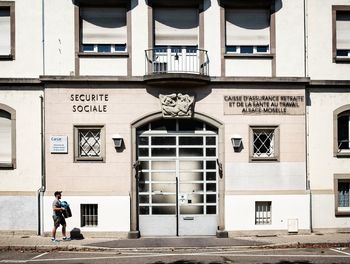 Woman on footpath against building