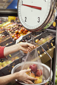 Cropped image of man weighing apples at supermarket