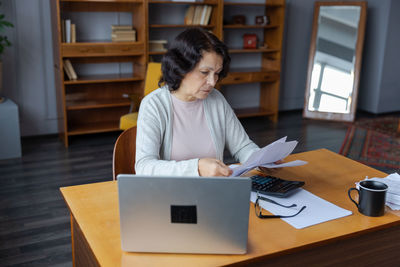 Side view of woman using laptop at home