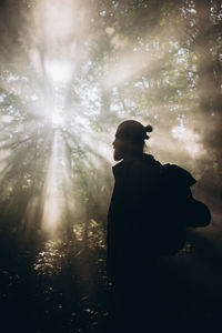 Man with backpack walking in forest against trees