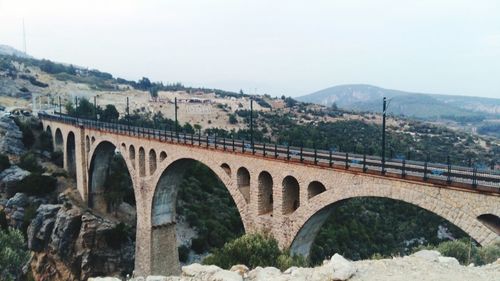 Arch bridge over mountains against sky