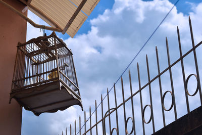 Low angle view of metal fence against sky