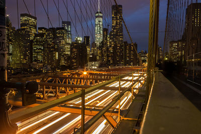 Blurred motion of light trails on bridge against sky at night