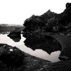 Rock formations by sea against clear sky