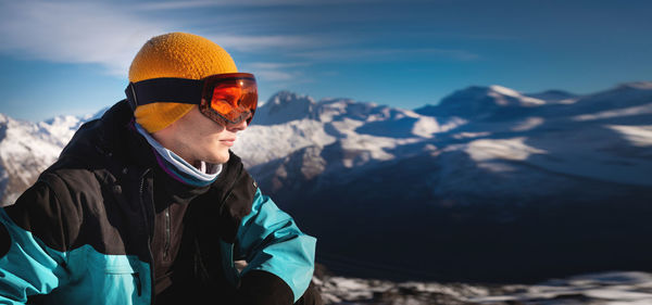 Young man in ski goggles on a snowy mountain on a sunny day. close-up of a man looking to the side