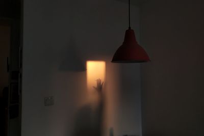 Silhouette person holding illuminated lamp at home