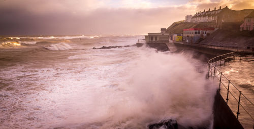 Waves splashing on pier during sunset