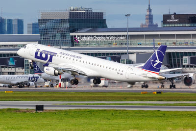 Airplane on airport runway against sky in city