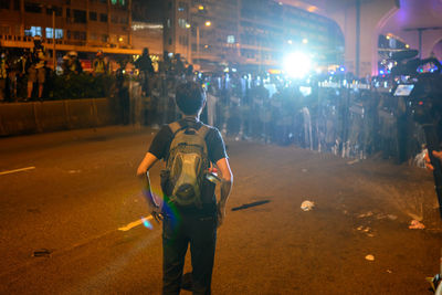 Rear view of people walking on illuminated street at night