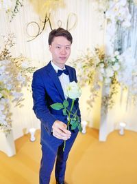 Portrait of young man standing against white wall