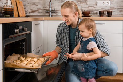 Father and kid waiting for freshly baked buns bread, cinnabons or pastry near the oven happy time