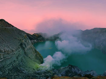 Smoke emitting from volcanic mountain against sky during sunset