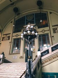 Low angle view of electric lamp hanging on building