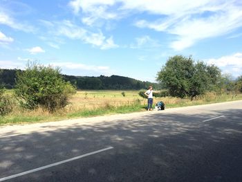 Man cycling on road against sky