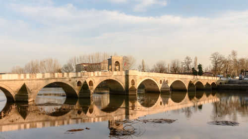 Arch bridge over river against sky